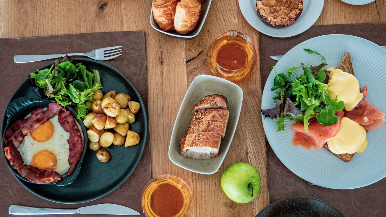 Assiette raffinée avec viennoiseries, fruits frais et boissons chaudes lors d’un brunch convivial avant une séance de thalassothérapie.