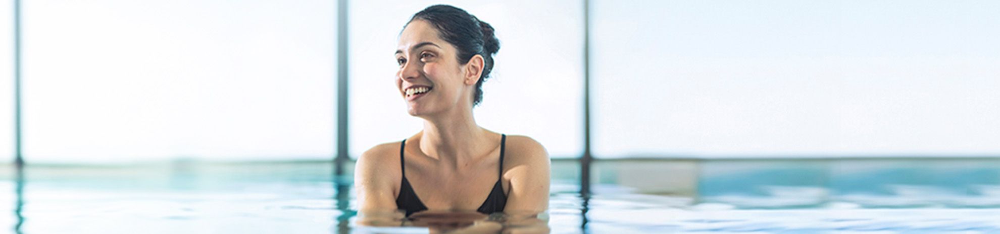 Femme souriante dans piscine vue mer