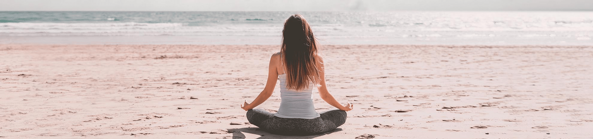 femme seule faisant du yoga sur la plage face à la mer