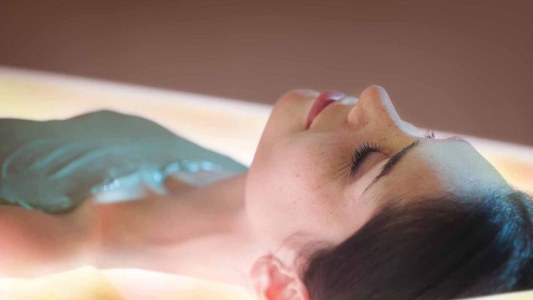 Femme recevant un soin enveloppement de crème d'algues laminaires sur lit hydrosensoriel