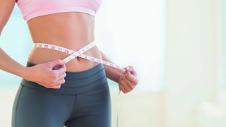 Femme qui mesure son tour de taille avec un mètre