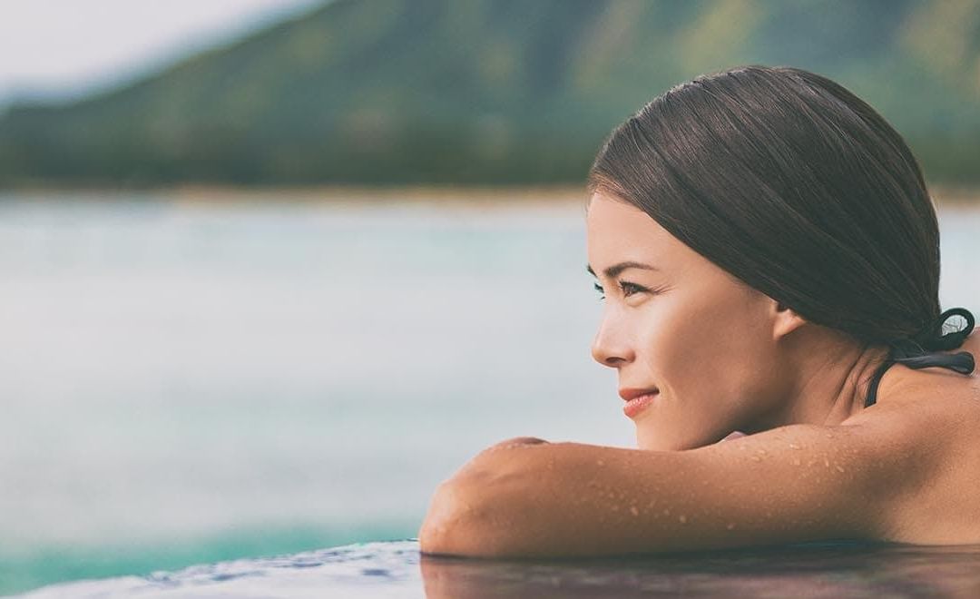 femme au bord d'une piscine avec vue mer
