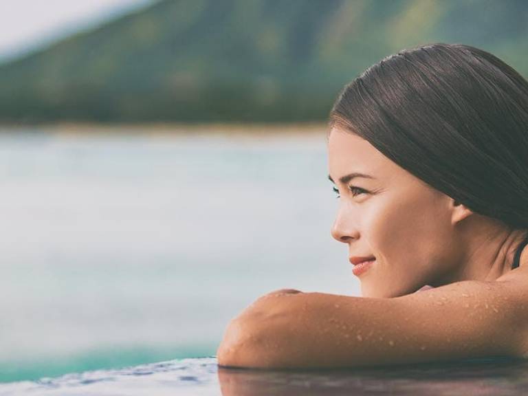 femme au bord d'une piscine avec vue mer