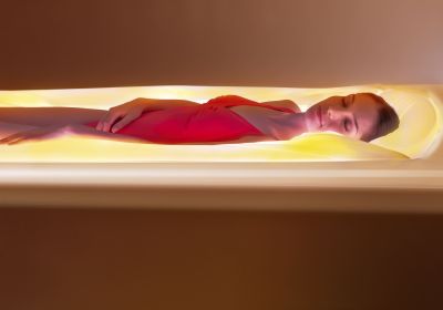 Femme détendu et allongé dans une capsule diffusant une lumière doré