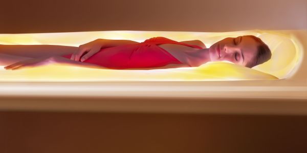 Femme détendu et allongé dans une capsule diffusant une lumière doré