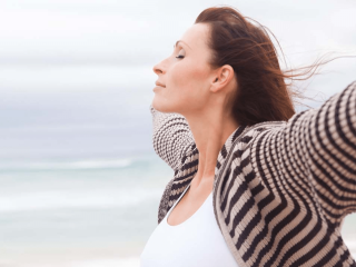 Femme avec les bras ouverts sur une plage