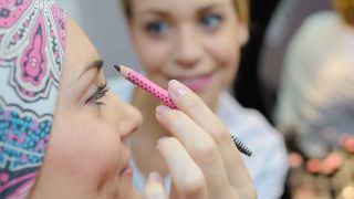 personne appliquant un crayon de maquillage sur un visage