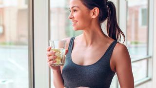 Femme qui tient un verre d'eau pour favoriser l'hydratation