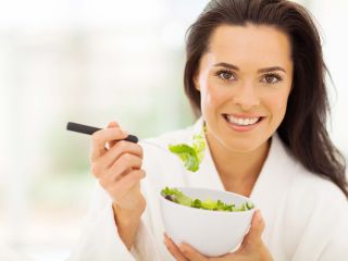 Femme en peignoir qui mange une salade