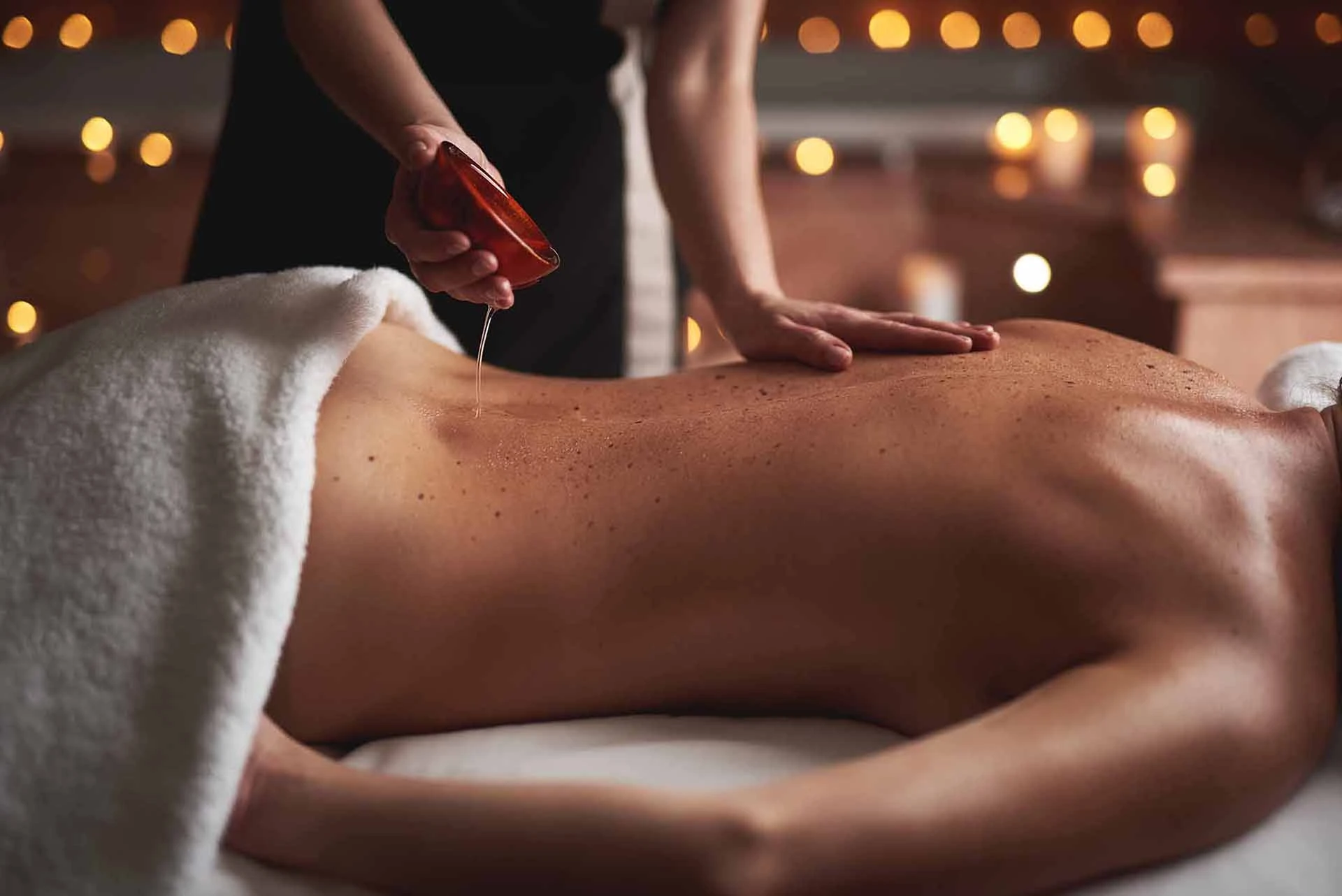 personne réalisant un massage aux huiles essentielles apaissantes sur le dos d'une femme